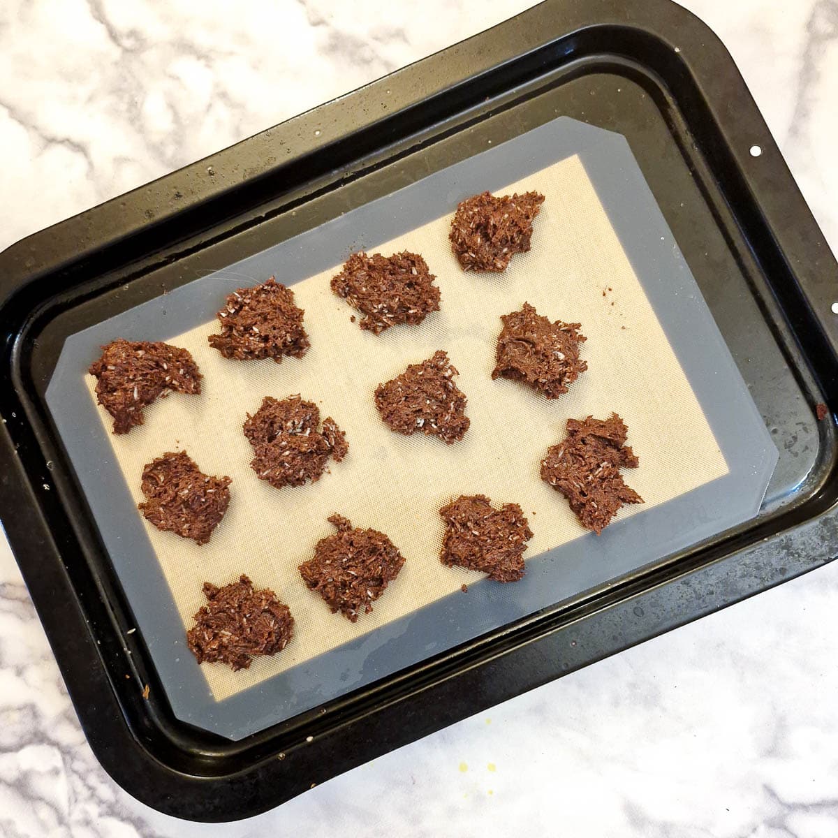 12 teaspoons of biscuit batter on a baking tray.