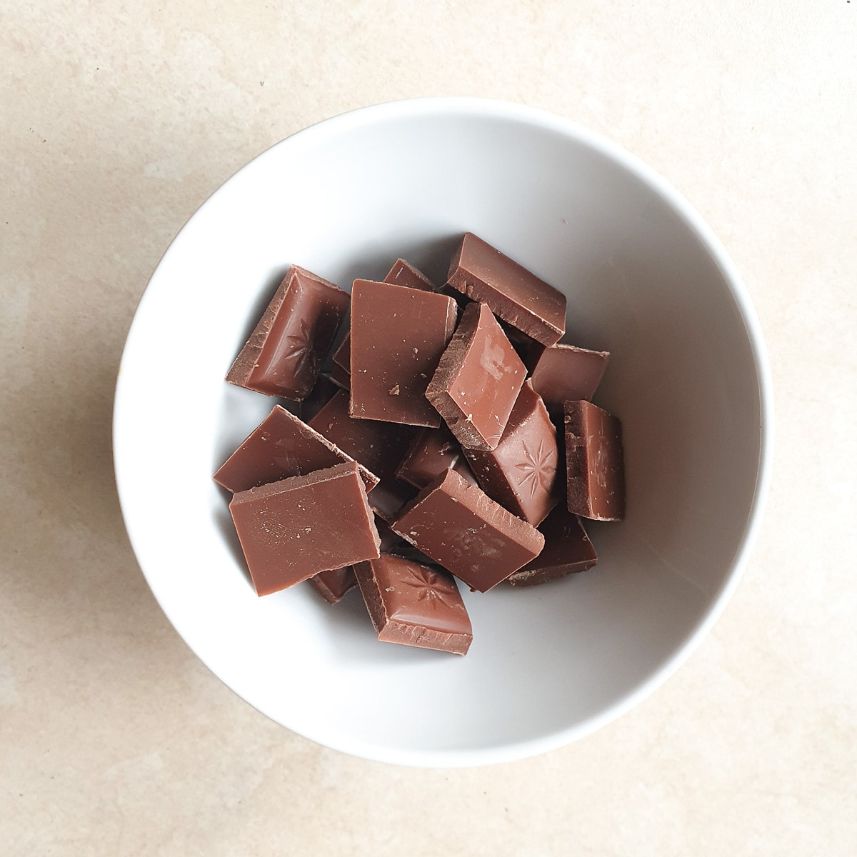 Pieces of chocolate broken into a small white bowl.