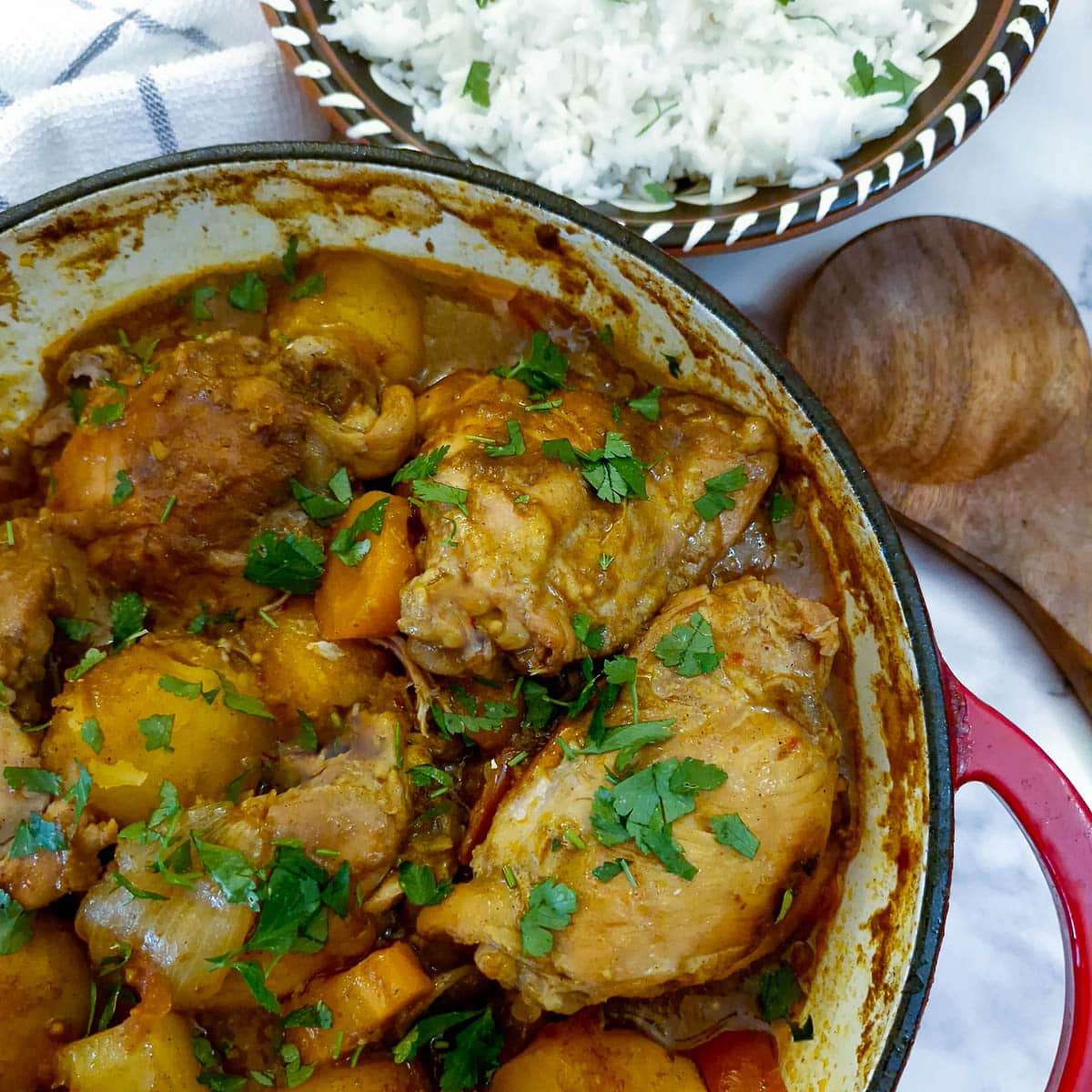 Overhead view of a dish of chicken curry with a bowl of white rice.
