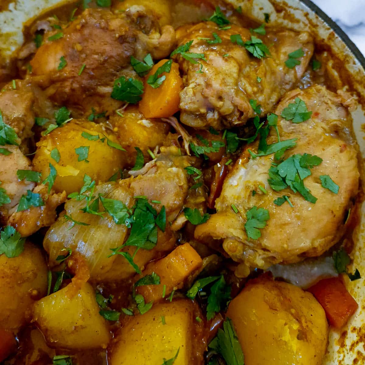 Close up of chicken curry garnished with chopped parsley.