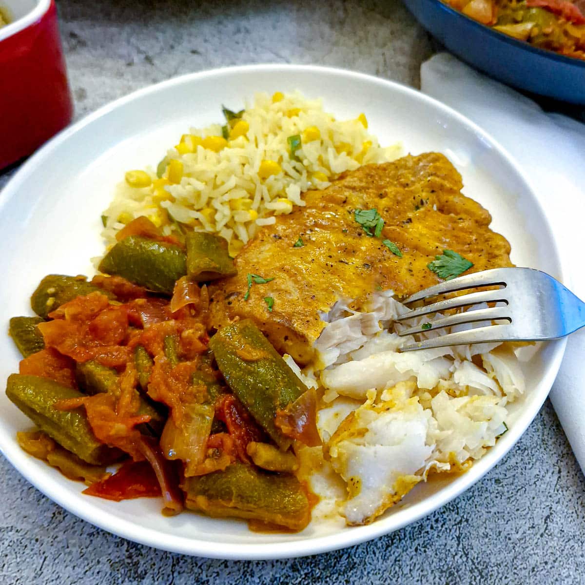 A plate of cod, green beans and rice, with the fish being flaked with a fork.