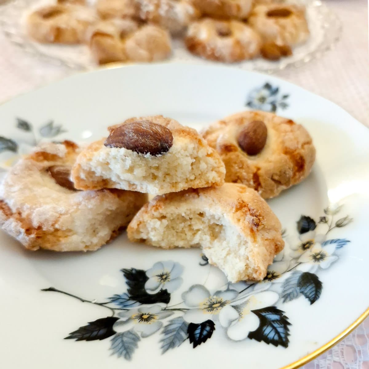 Three lemon cookies on a plate with one broken in half to show the texture.