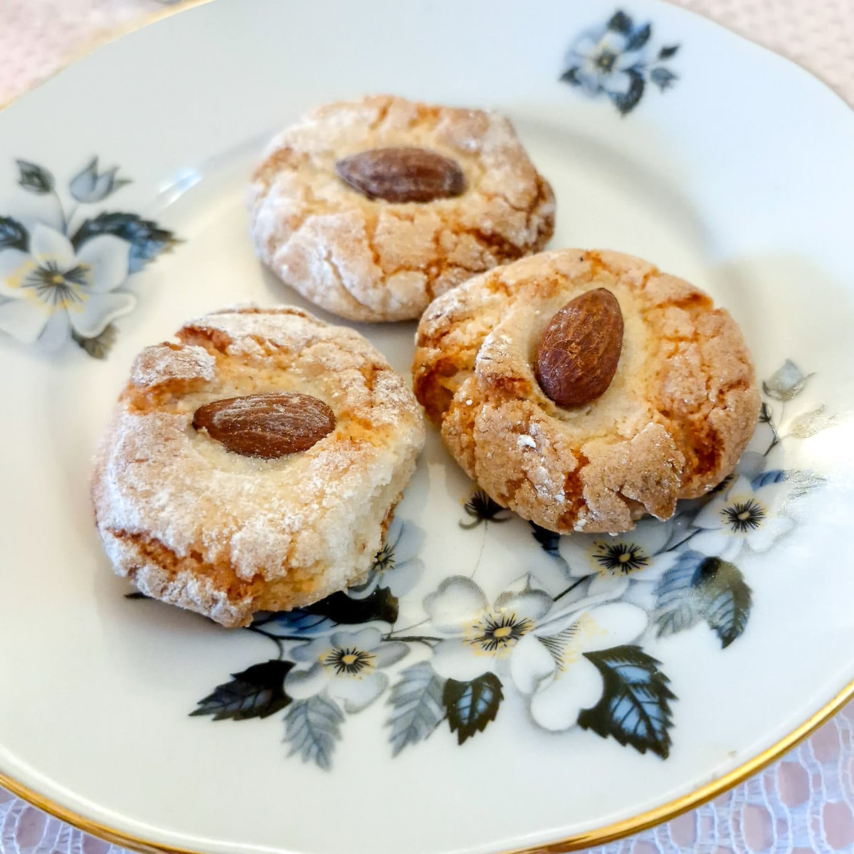 Three lemon amaretti cookies on a blue patterned plate.