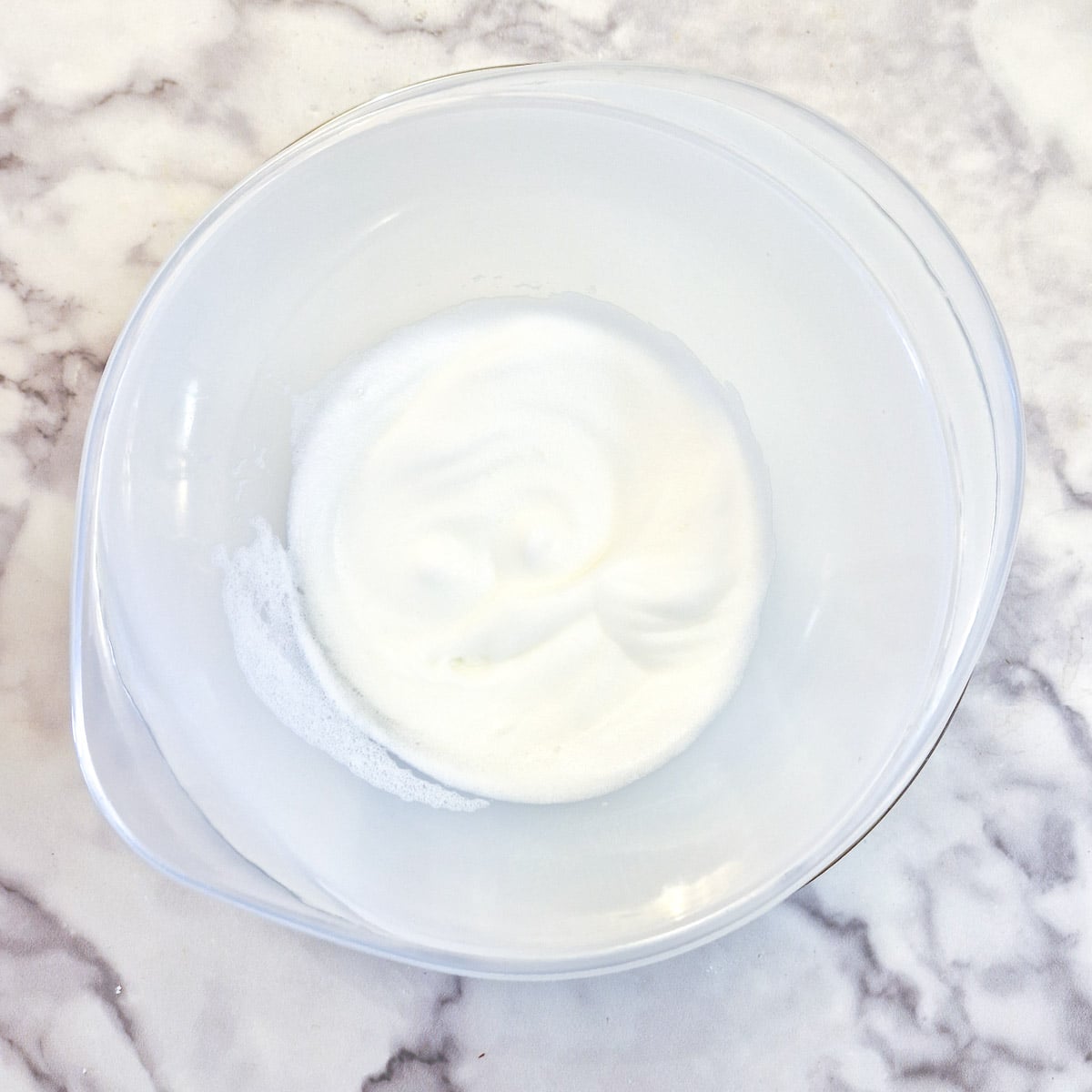 Stiffly beaten egg whites in a bowl.