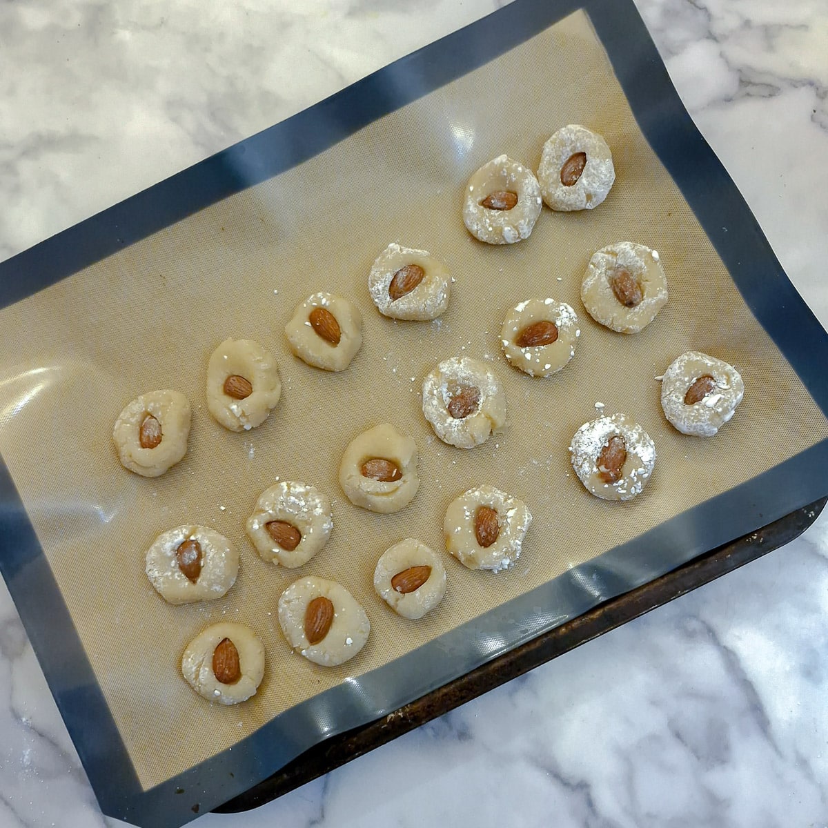 A baking sheet of unbaked amaretti cookies.