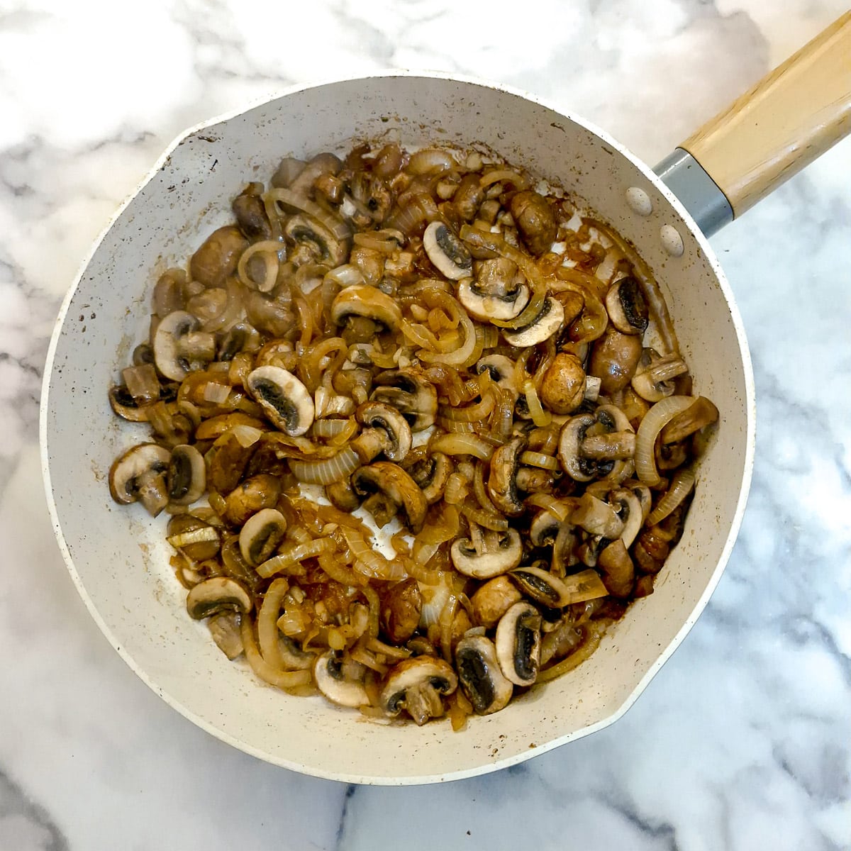 Onions and mushrooms in a frying pan.