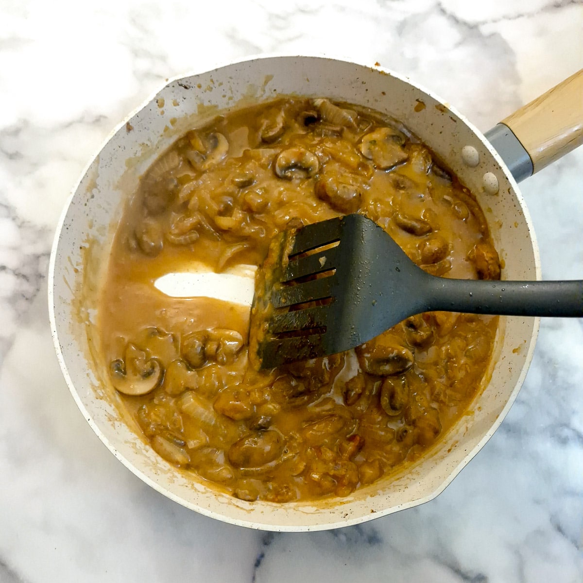 Thickened stock in a frying pan with a spatula drawing a trail through the stock.
