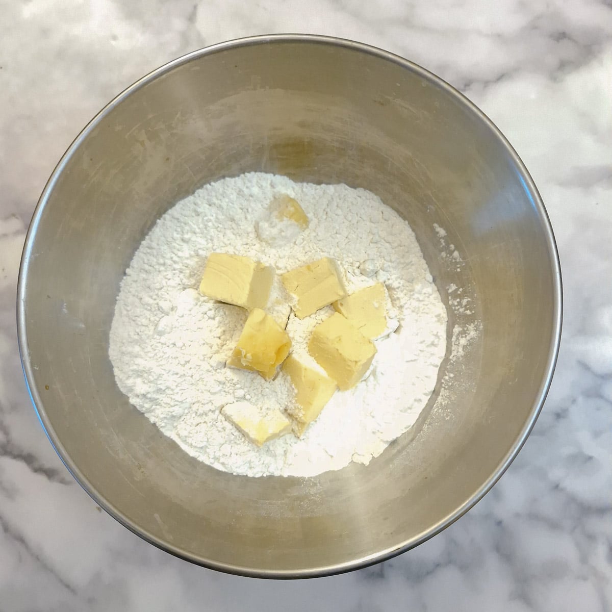 Flour and cubed butter in a mixing bowl.