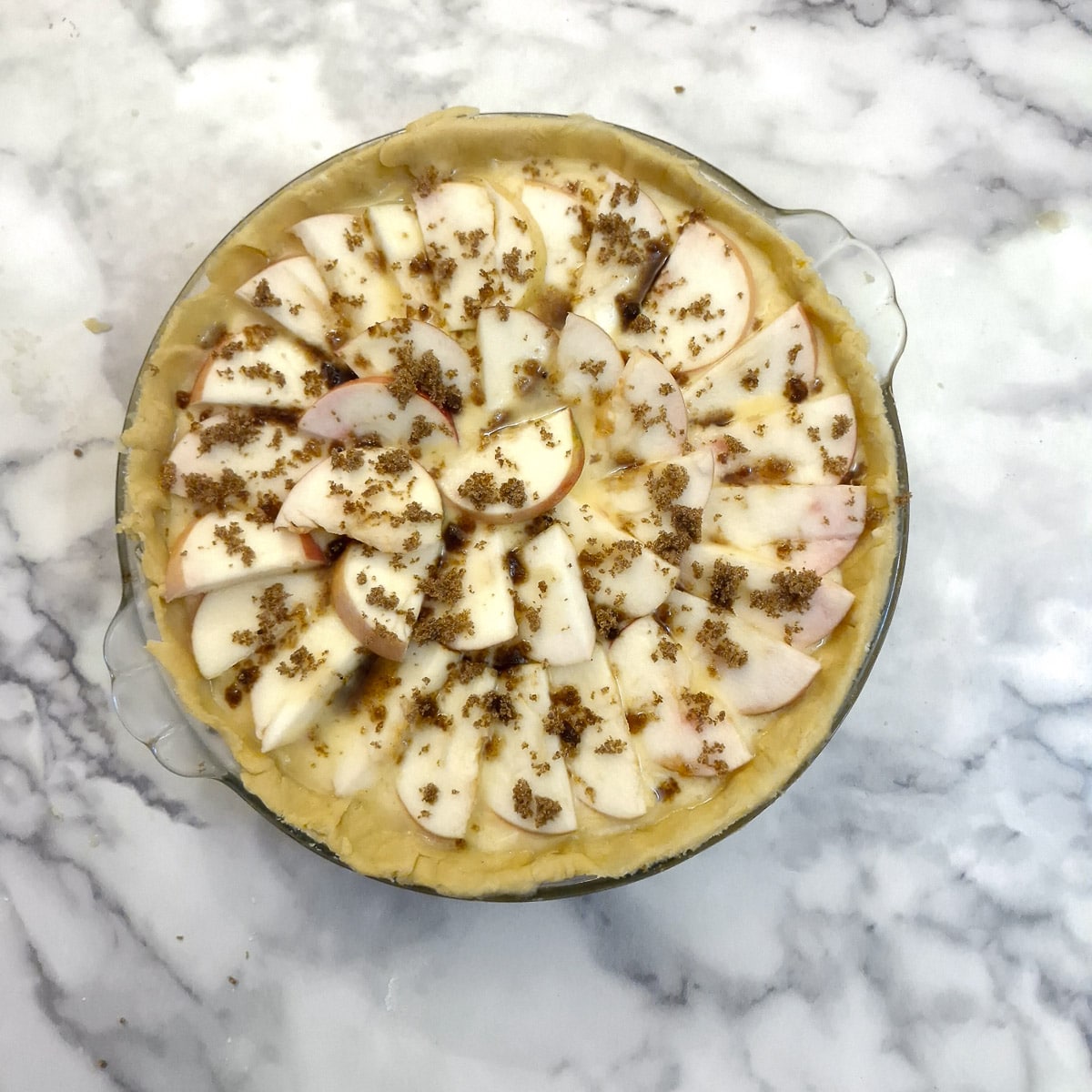 Sliced apples arranged on top of the tart, with a sprinkling of demerara sugar on top.