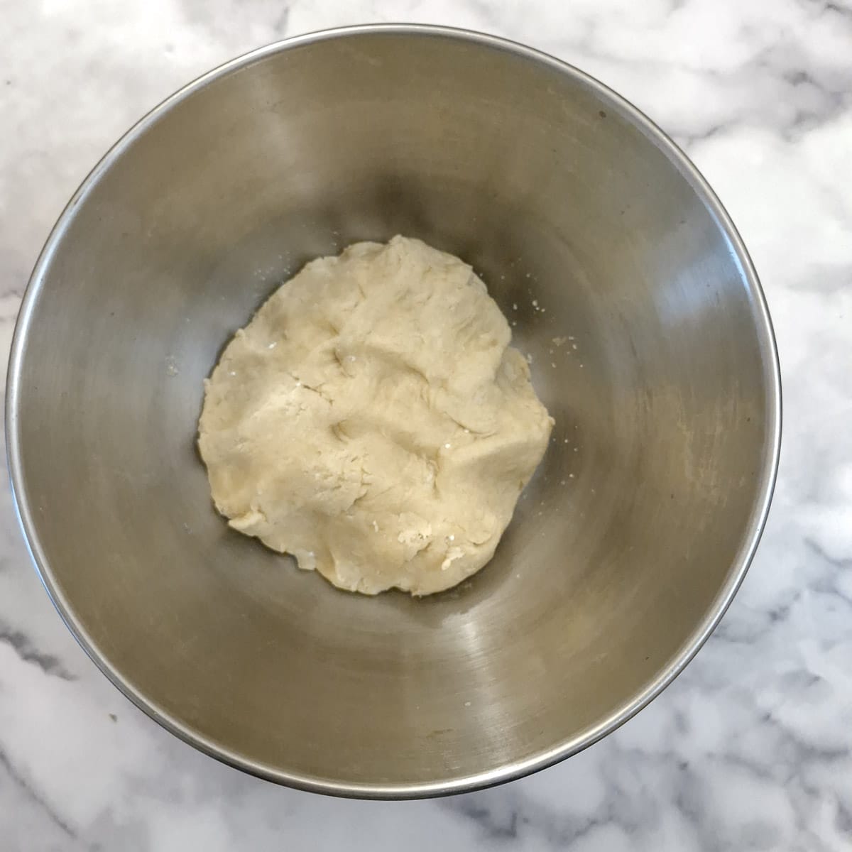 A ball of pastry in a mixing bowl.