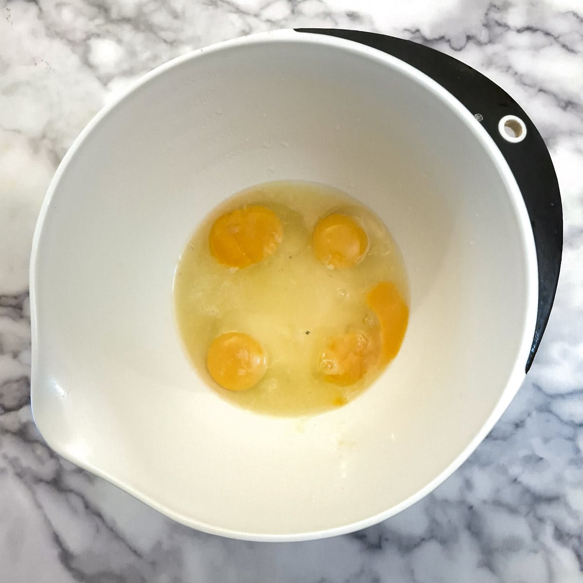 4 eggs with sugar in a mixing bowl.