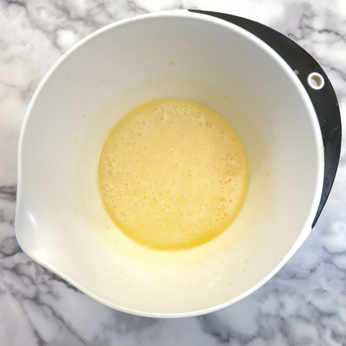 Melted butter added to the eggs and sugar in a mixing bowl.