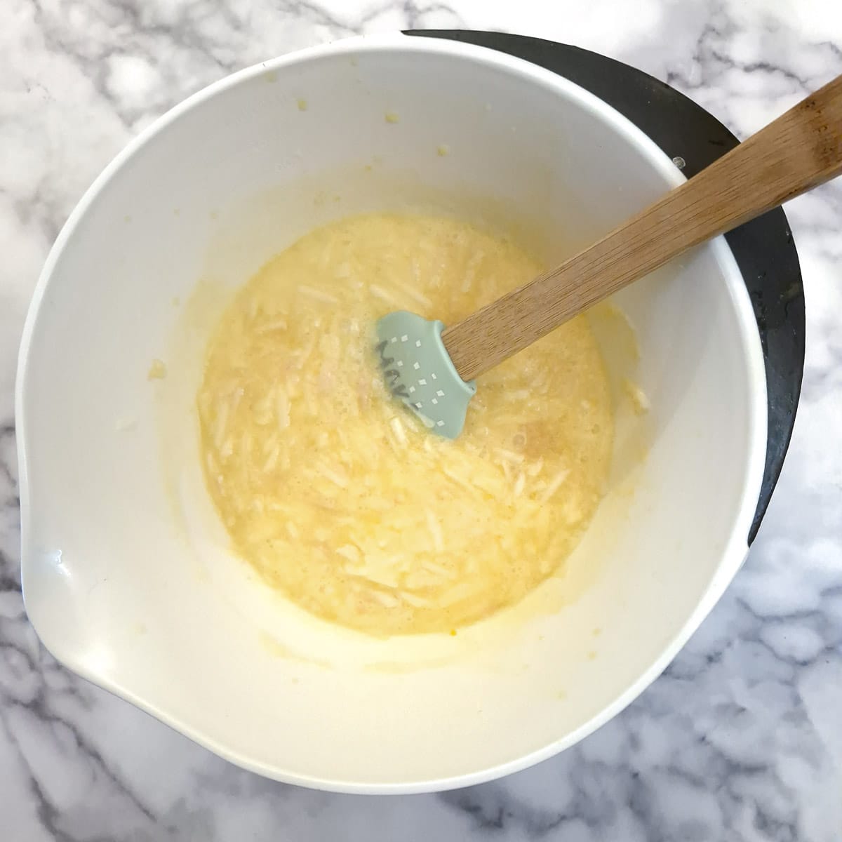 Grated apples added to the Canterbury tart filling in a mixing bowl.
