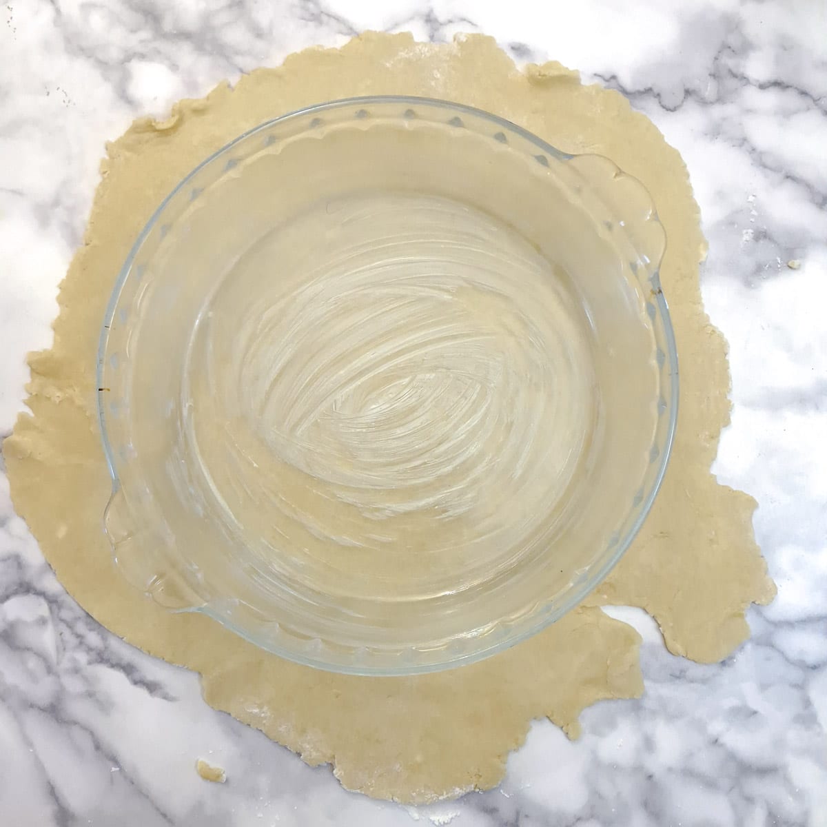 Pastry rolled out into a circle with a baking dish on top to show the size the pastry should be rolled to.