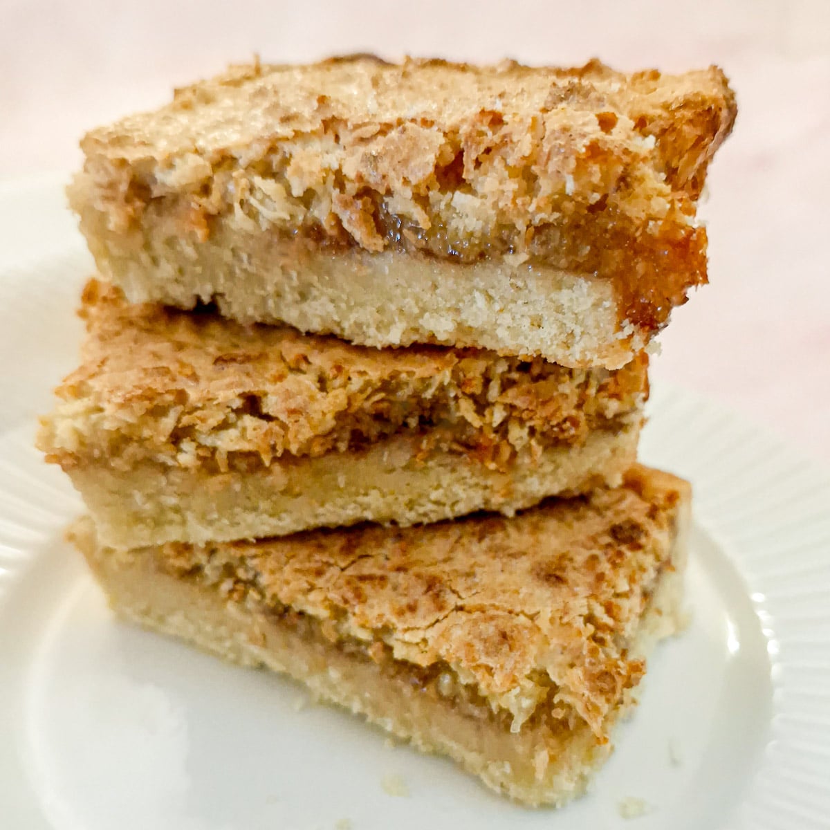Three slices of coconut jam tart piled one on top of the other.