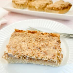A slice of coconut jam tart on a white plate.