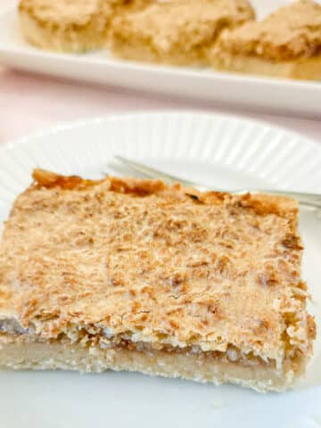 A slice of coconut jam tart on a white plate.
