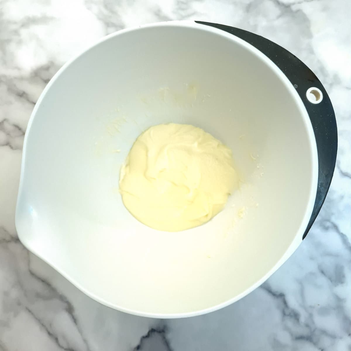 Butter and sugar creamed together in a white mixing bowl.