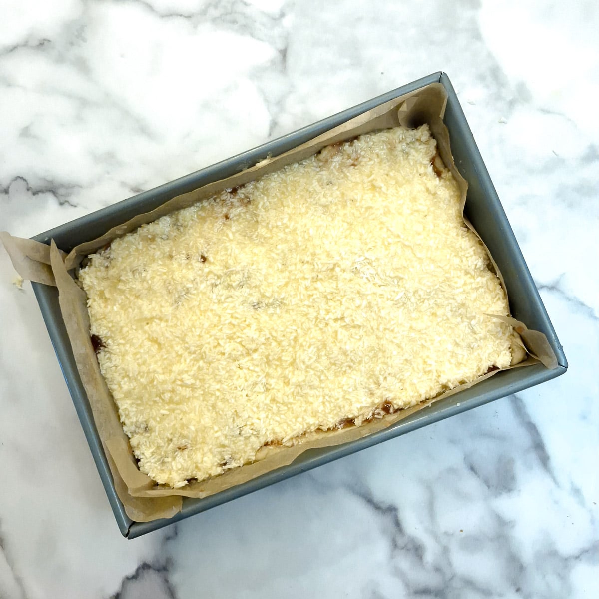 Coconut topping spread on top of the layer of jam.