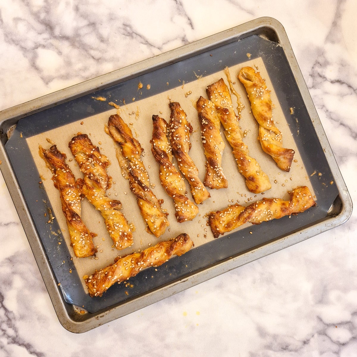 Cooked cheese straws on a baking tray.