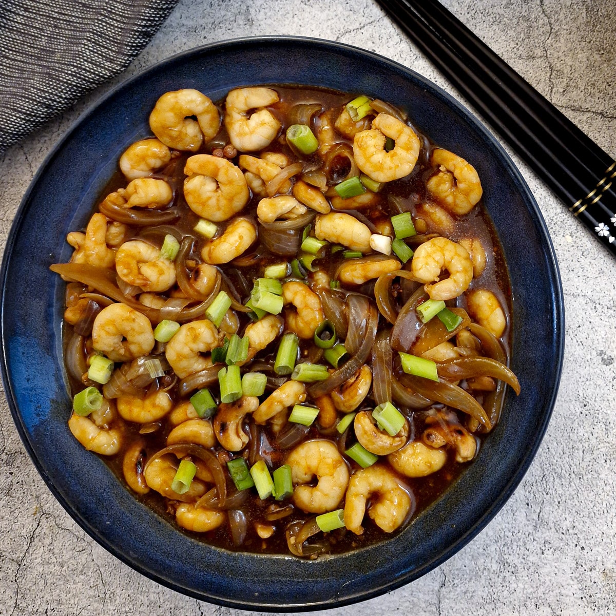 The finished dish of kung pao prawns garnished with chopped spring onions.
