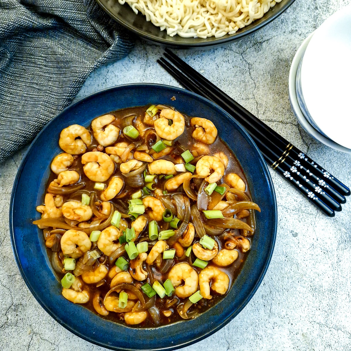 A dark blue serving dish filled with kung pao prawns and cashews.
