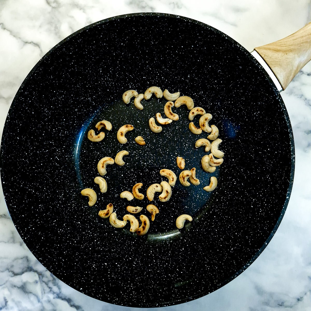 Cashew nuts toasting in a wok.