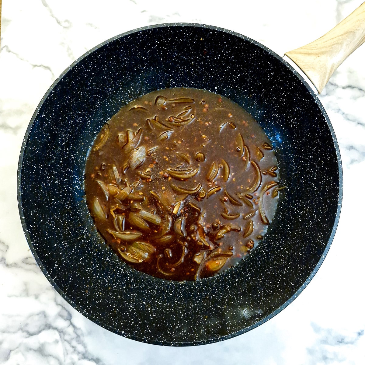 Sauce ingredients added to onions in a wok.