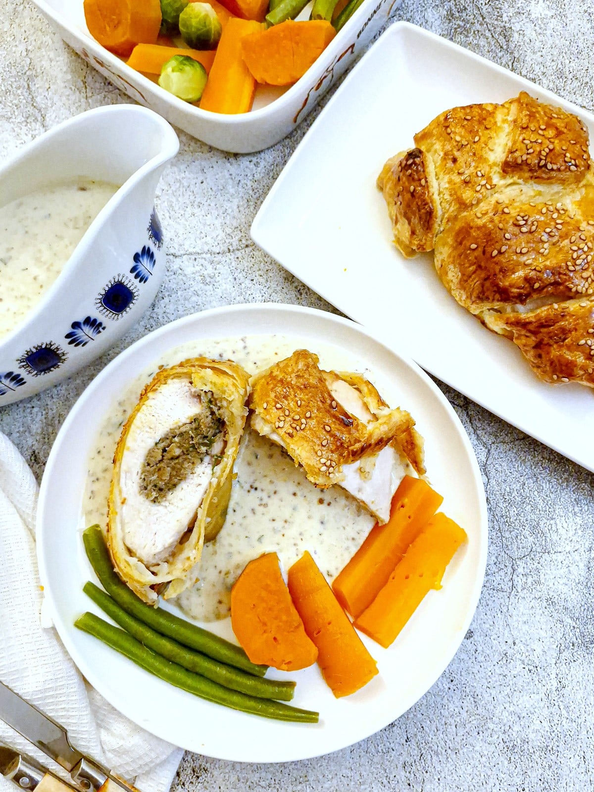 Overhead shot of slices of mushroom-stuffed chicken parcels on a white plate with vegetables.