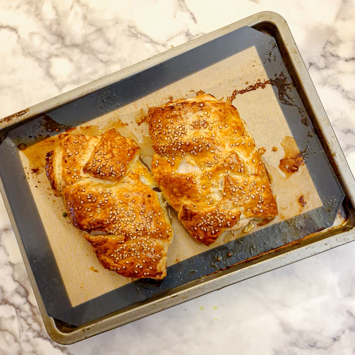 2 baked chicken and mushroom parcels on a baking tray.