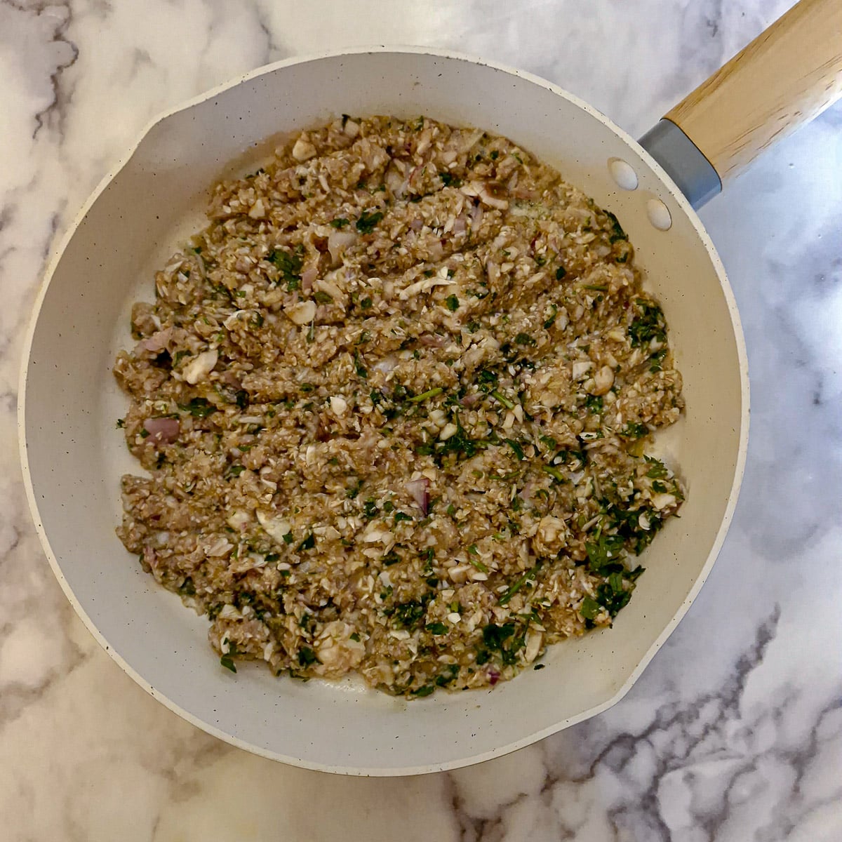 Chopped mushrooms, shallots and herbs in a frying pan.