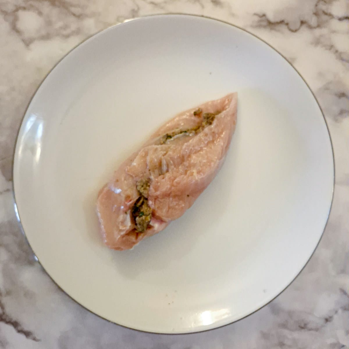 A mushroom-stuffed chicken breast on a white plate.