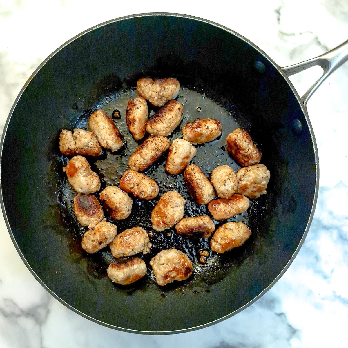 Browned sausage balls in a frying pan.