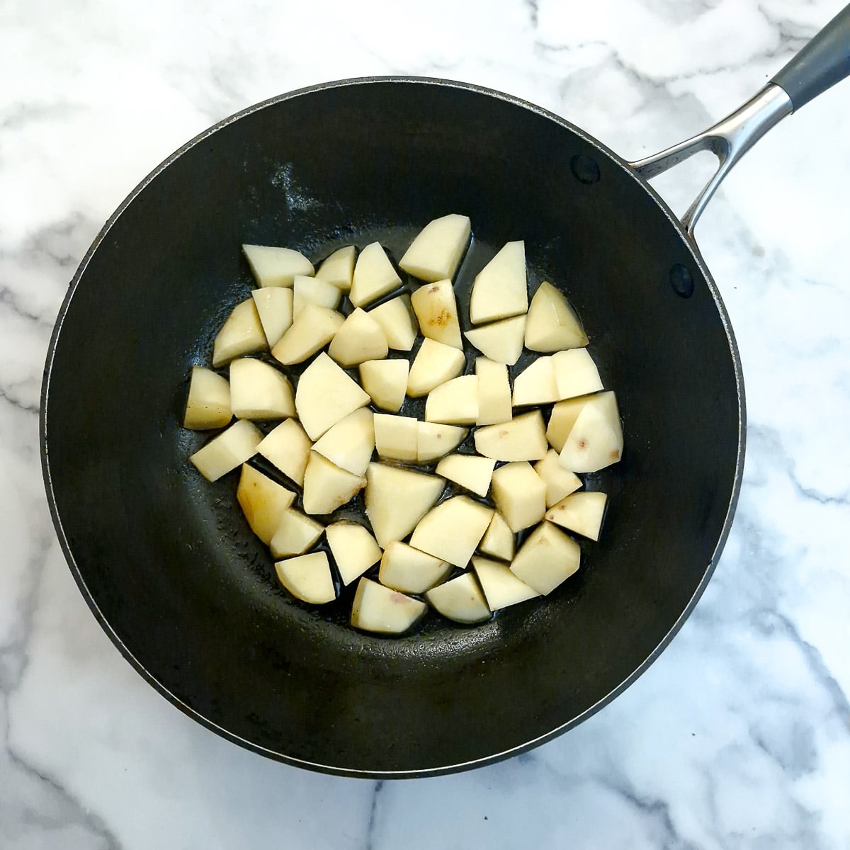 Cubed potatoes in a frying pan.