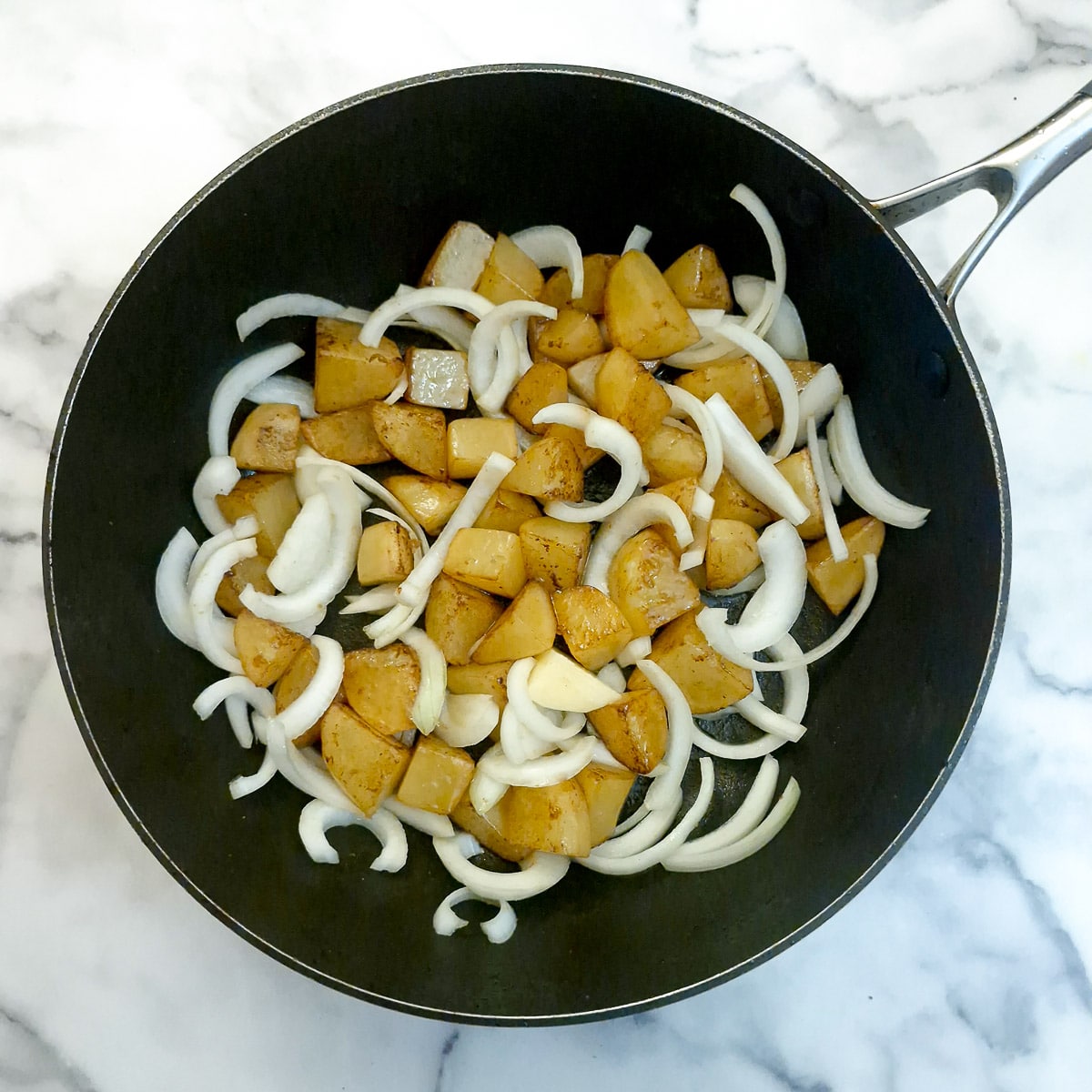 Potatoes and onions in a frying pan.