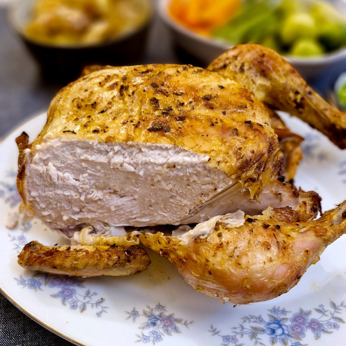 A whole cooked chicken with part of the breast removed.