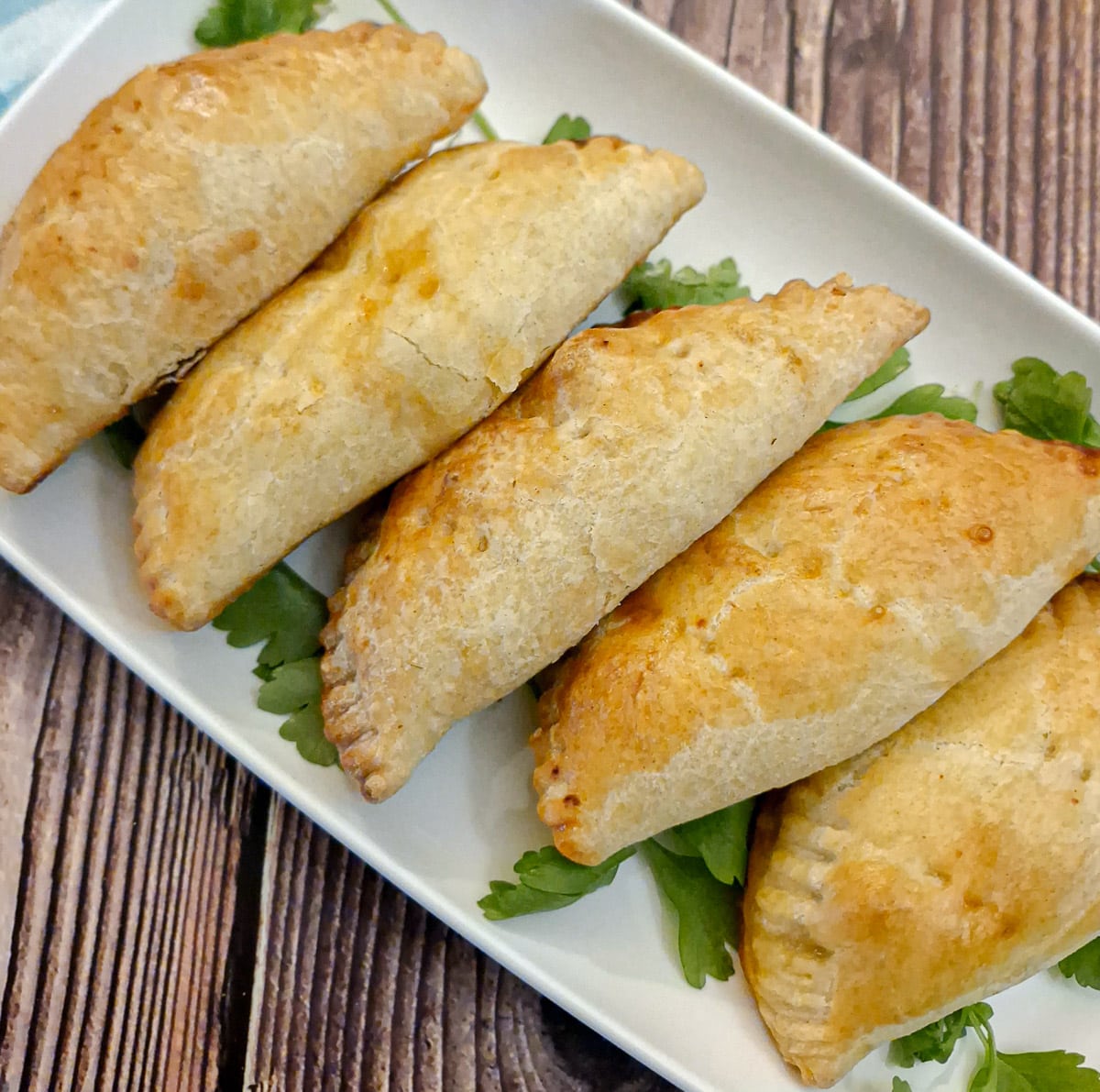 5 empanadas on a white oblong plate.