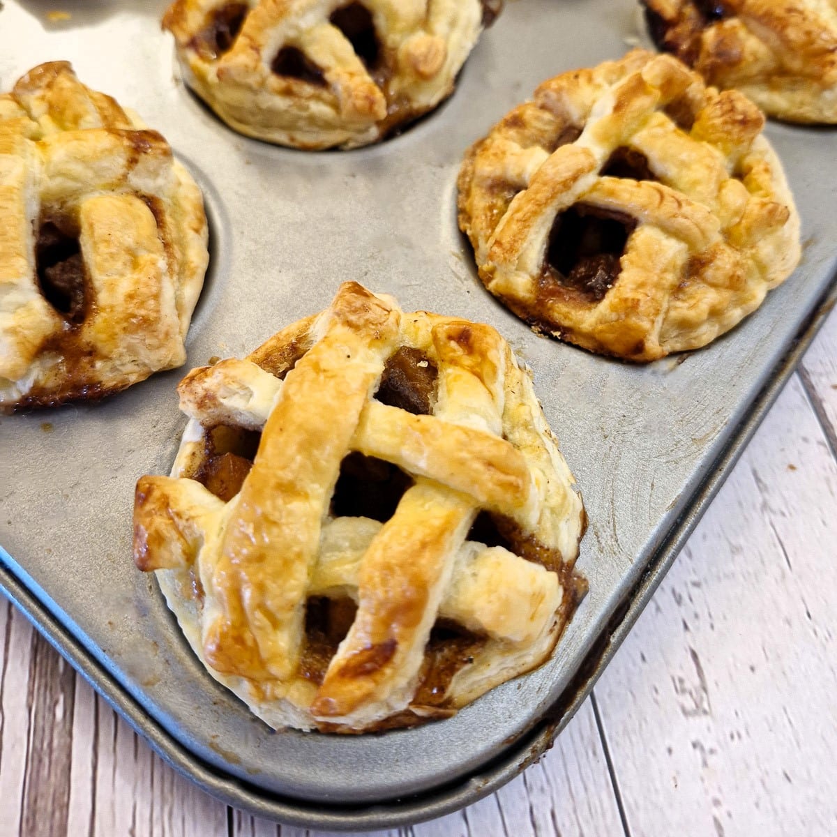 Close up of caramel apple pies in a baking tray.