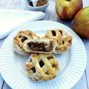 Three caramel apple pies on a plate with one cut open to show the inside.