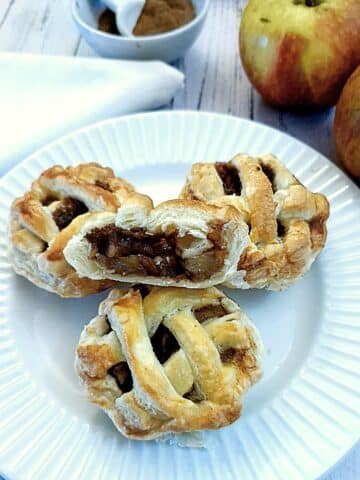 Three caramel apple pies on a plate with one cut open to show the inside.