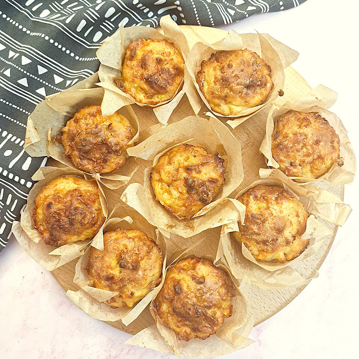 9 cornbread muffins on a wooden board.