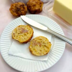 Two halves of a cheese and bacon cornbread muffin showing the inside.
