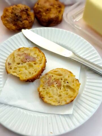 Two halves of a cheese and bacon cornbread muffin showing the inside.