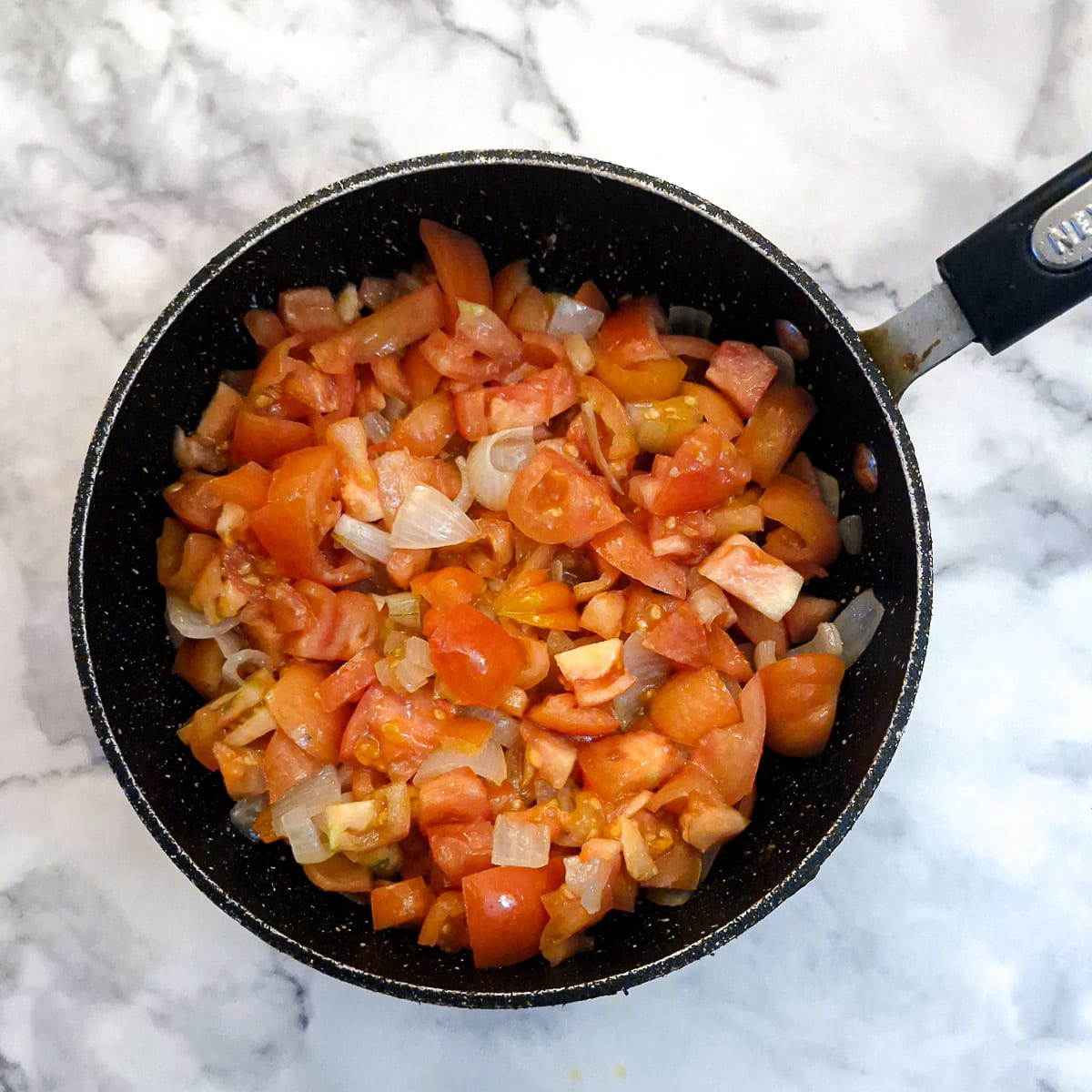 Chopped tomatoes with onions in a saucepan.