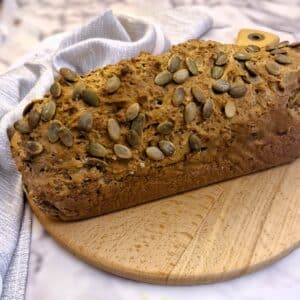A loaf of seeded Irish soda bread on a wooden board.