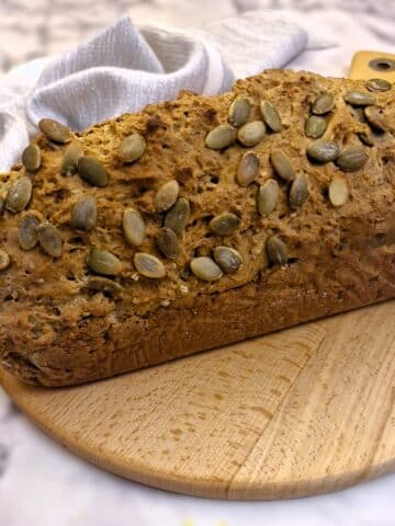 A loaf of seeded Irish soda bread on a wooden board.