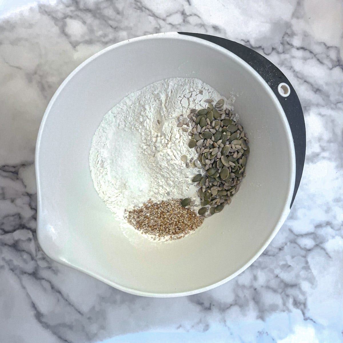 Dry ingredients and seeds in a mixing bowl.