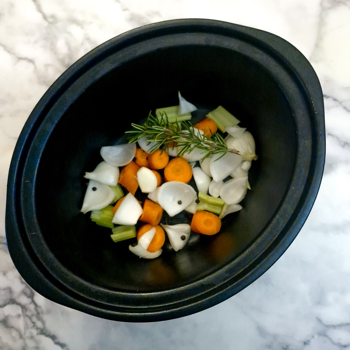 Chopped carrots, onions and celery  in a slow cooker.
