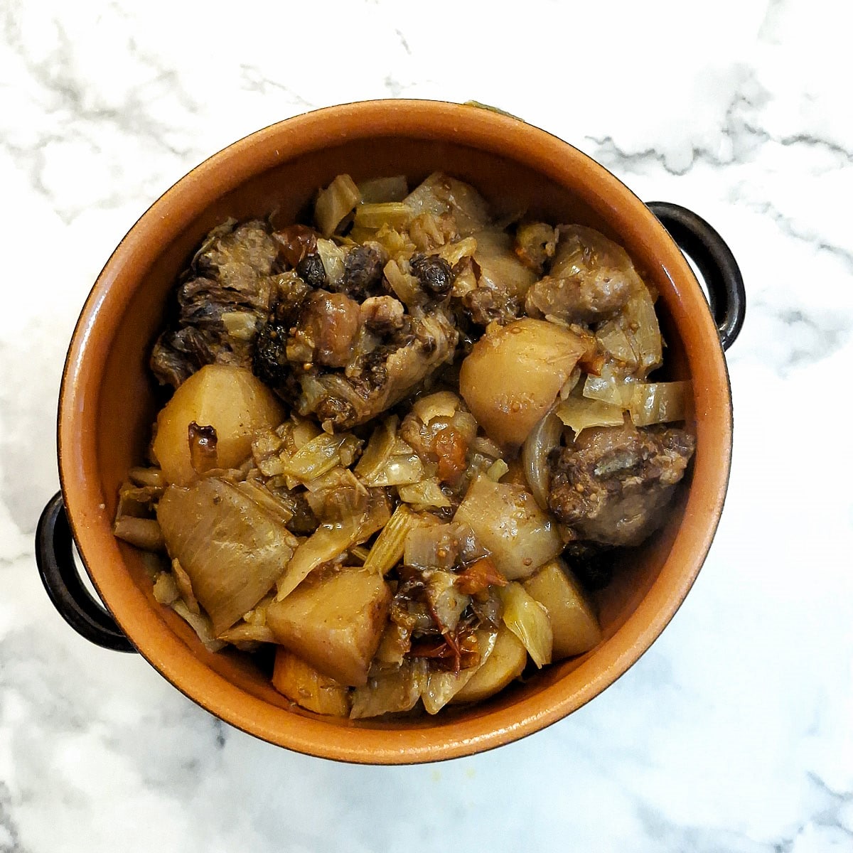 Cooked oxtail and vegetables transferred to a casserole dish.