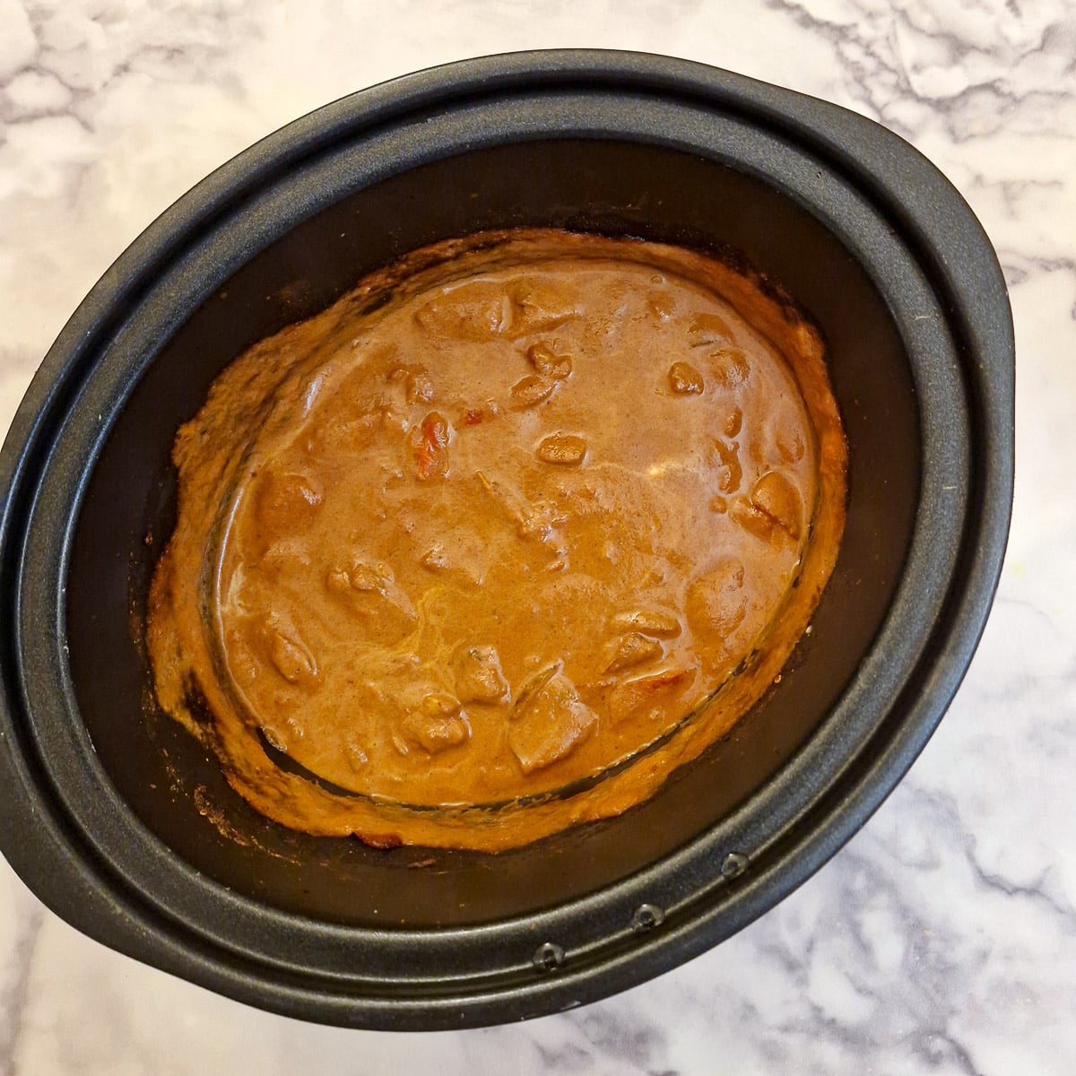 Cooked chicken tikka masala in a slow cooker after the yoghurt and cream has been added.